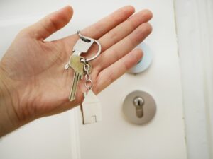 Keys being held in front of a white locked door